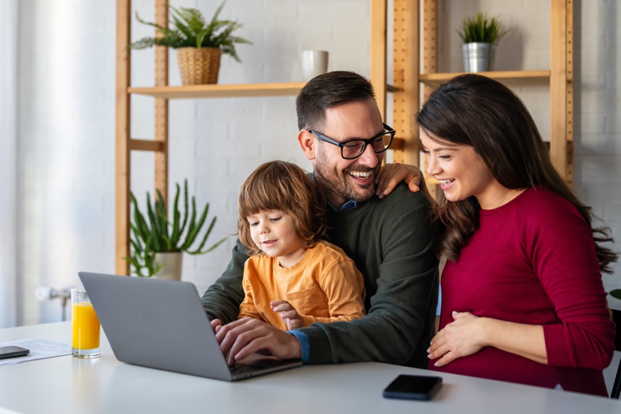 Parents,And,Child,Relaxing,At,Home,With,Computer,Watching,Funny